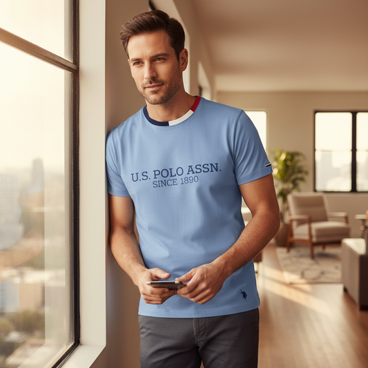 Hombre vistiendo camiseta azul claro de algodón www.treshop.com.co con cuello redondo y logo U.S. POLO ASSN. impreso