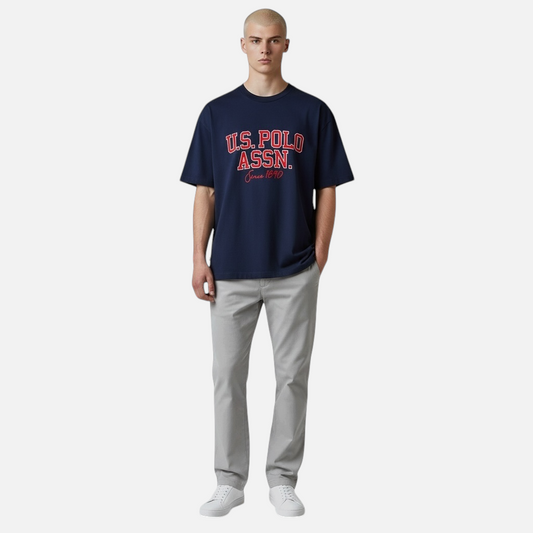Hombre con camiseta azul marino de manga corta U.S. POLO ASSN. con logo rojo, combinada con pantalones grises