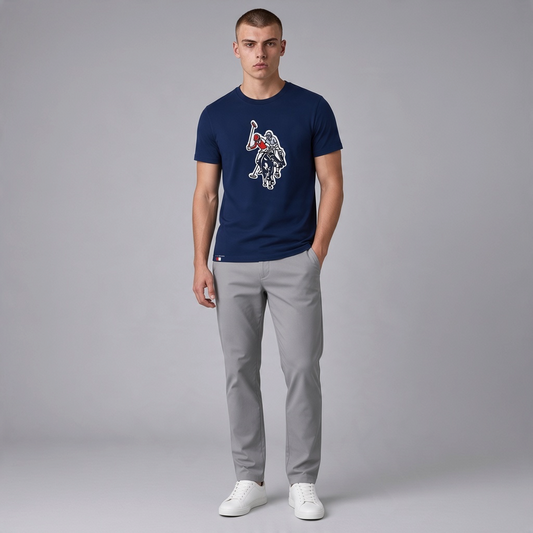 Hombre vistiendo camiseta azul marino de algodón U.S. POLO ASSN. con estampado frontal y pantalones grises