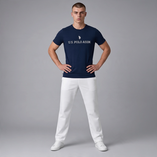 Hombre vistiendo camiseta azul marino de algodón U.S. POLO ASSN. con logo frontal y pantalones blancos en www.treshop.com.co