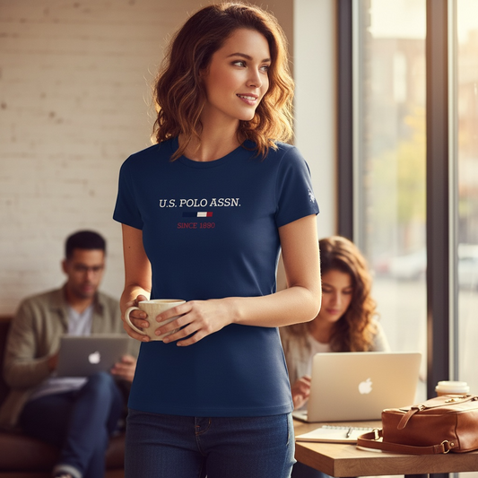 Mujer vistiendo camiseta azul marino U.S. POLO ASSN. con logo en el pecho en una cafetería con estilo casual.