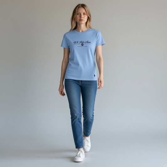 Mujer vistiendo camiseta azul claro de algodón U.S. Polo Assn. con logo y estampado, disponible en www.treshop.com.co