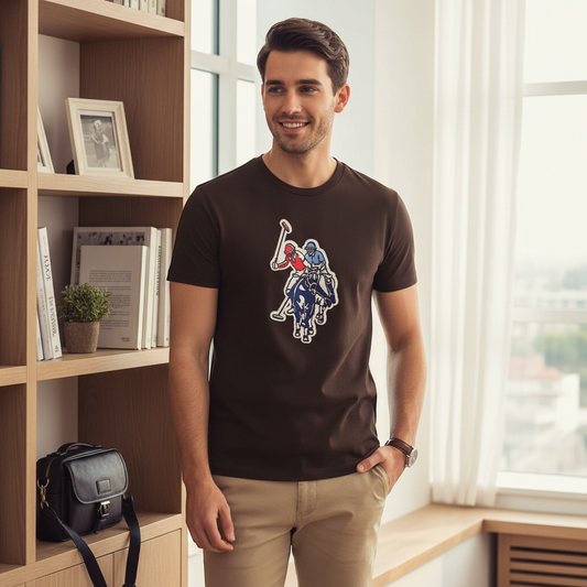 Hombre vistiendo camiseta marrón de algodón U.S. Polo Assn. con estampado deportivo central en un interior luminoso.