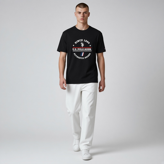 Hombre vistiendo camiseta negra de algodón U.S. Polo Assn. con estampado frontal y pantalones blancos casuales