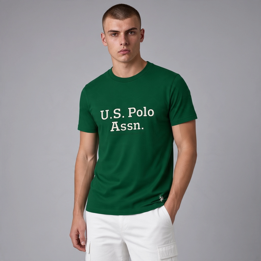 Hombre vistiendo camiseta verde de algodón U.S. Polo Assn. con logo estampado en el pecho y detalle bordado en www.treshop.com.co