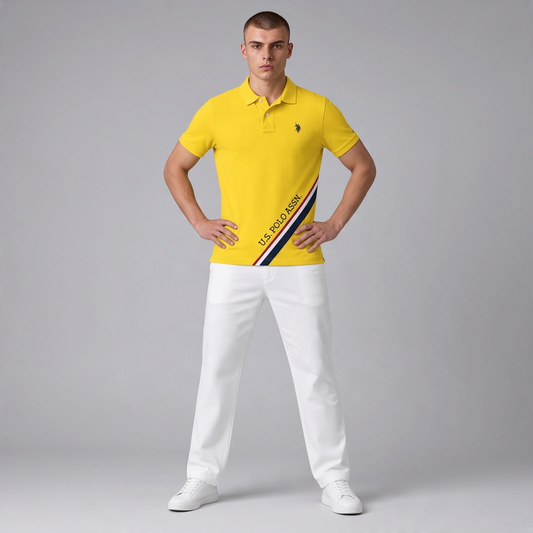 Hombre vistiendo polo amarillo de algodón www.treshop.com.co con franja diagonal y logo bordado, combinado con pantalón blanco.