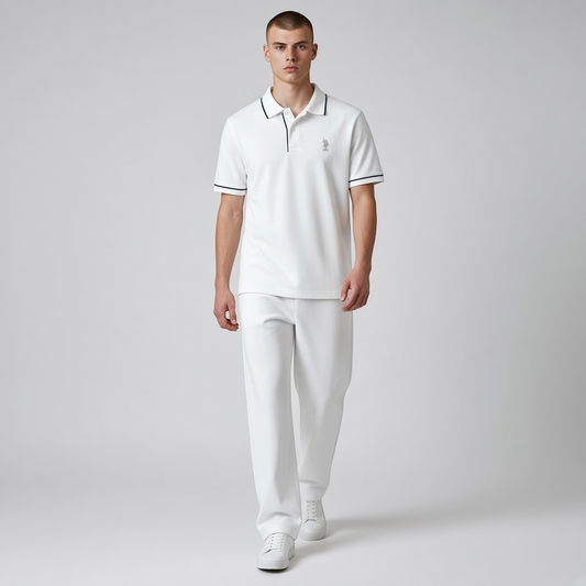 Hombre vistiendo polo blanco www.treshop.com.co con detalles en contraste, logo bordado y pantalones blancos a juego.
