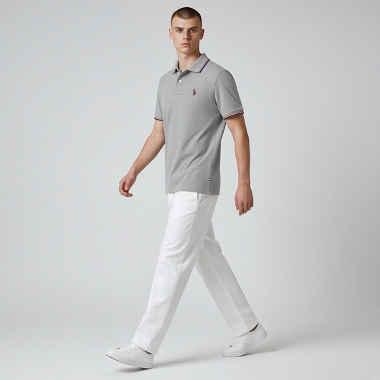 Modelo vistiendo polo gris de algodón www.treshop.com.co con ribetes tricolor y logo bordado, combinado con pantalón