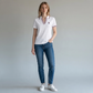 Modelo vistiendo polo blanco www.treshop.com.co con cuello en V y detalles tricolores, combinado con jeans azules.