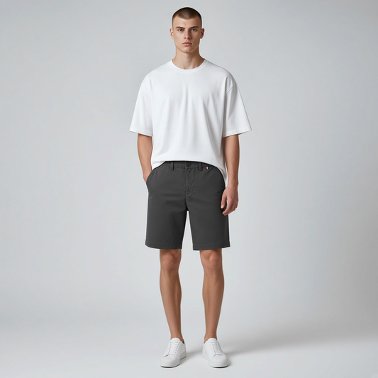 Hombre vistiendo bermuda gris oscuro de www.treshop.com.co con camiseta blanca y zapatillas en estudio