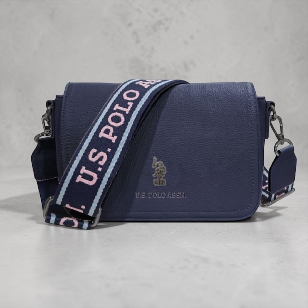 Bolso bandolera azul marino www.treshop.com.co con correa ancha ajustable y logo metálico U.S. Polo Assn.