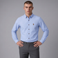 Hombre vistiendo camisa azul claro de manga larga www.treshop.com.co con cuello button-down y logo bordado en pecho