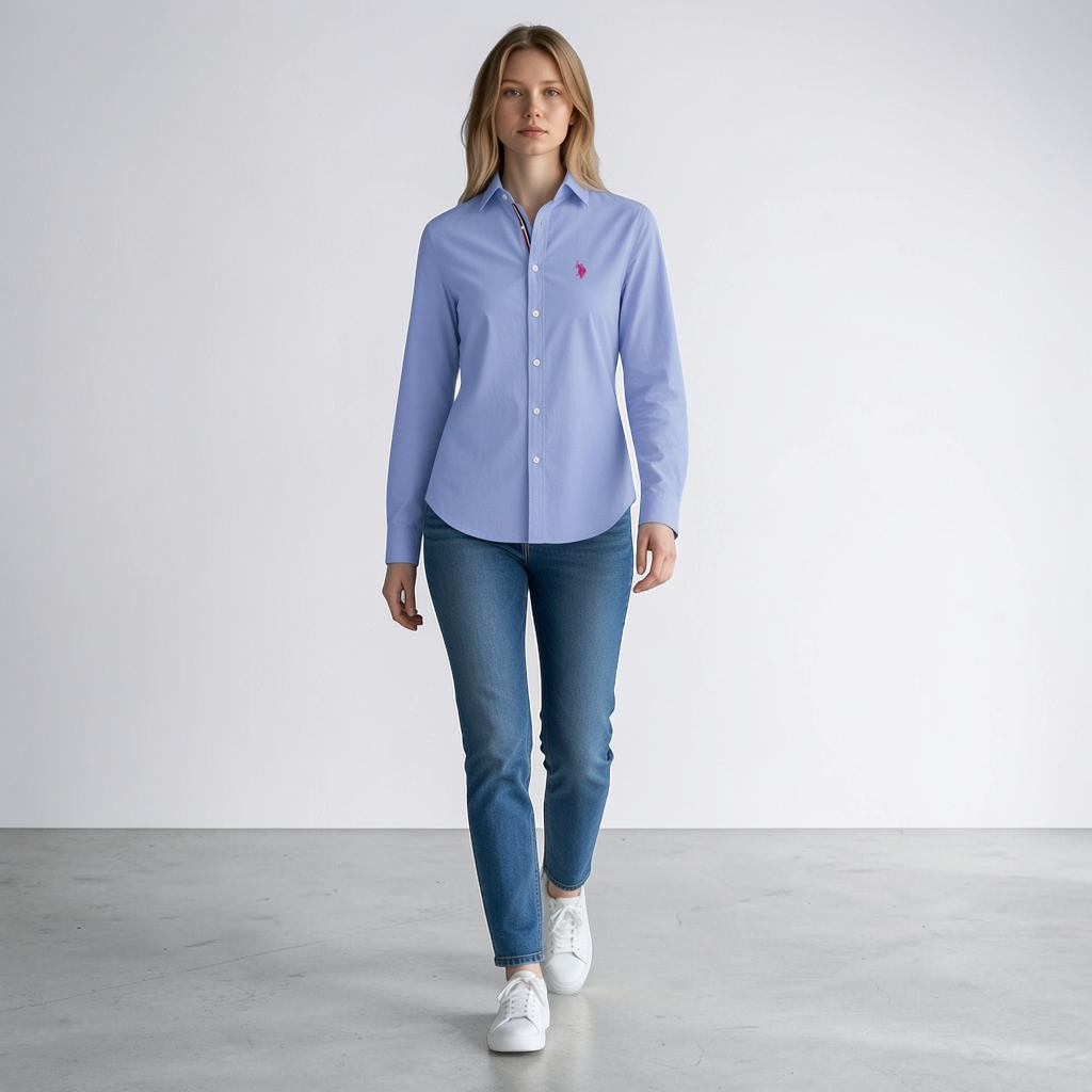 Modelo vistiendo camisa formal azul claro de manga larga www.treshop.com.co con logo bordado y jeans casuales