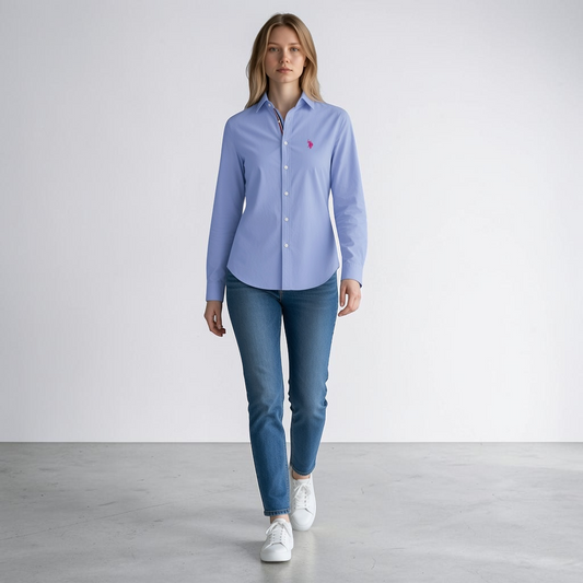 Modelo vistiendo camisa formal azul claro de manga larga www.treshop.com.co con logo bordado y jeans casuales