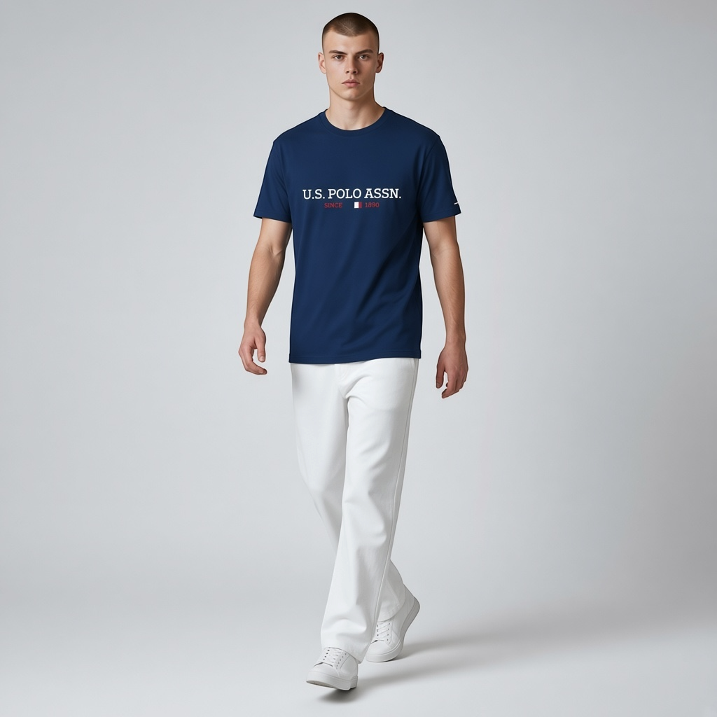 Hombre vistiendo camiseta azul marino de algodón U.S. POLO ASSN. con logo frontal, combinada con pantalones blancos.