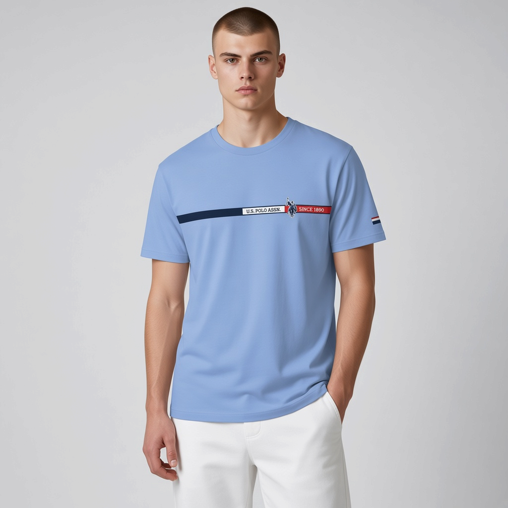 Hombre vistiendo camiseta azul claro U.S. Polo Assn. con estampado frontal y logo, disponible en www.treshop.com.co