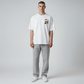 Hombre vistiendo camiseta blanca de algodón www.treshop.com.co con estampado gráfico en el pecho y pantalón gris