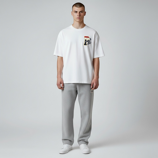 Hombre vistiendo camiseta blanca de algodón www.treshop.com.co con estampado gráfico en el pecho y pantalón gris