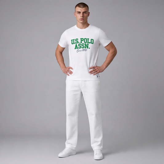 Hombre vistiendo camiseta blanca de algodón U.S. POLO ASSN. con estampado verde y pantalón blanco de www.treshop.com.co