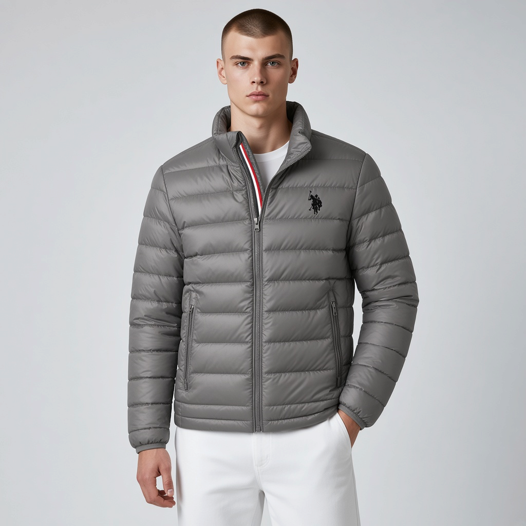 Hombre vistiendo chaqueta acolchada gris www.treshop.com.co con cuello alto, cremallera y logo bordado en el pecho