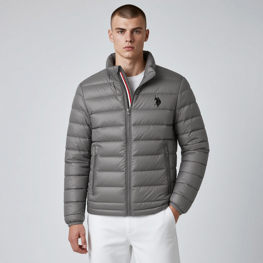 Hombre vistiendo chaqueta acolchada gris www.treshop.com.co con cuello alto, cremallera y logo bordado en el pecho