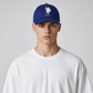Gorra deportiva azul www.treshop.com.co con logotipo USPA bordado en blanco, usada por un modelo con camiseta blanca