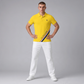 Hombre vistiendo polo amarillo de algodón www.treshop.com.co con franja diagonal y logo bordado, combinado con pantalón blanco.
