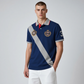 Hombre vistiendo polo azul marino www.treshop.com.co con banda diagonal gris, emblemas bordados y cuello en contraste