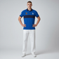 Hombre vistiendo polo azul real con franja azul marino y logo bordado de www.treshop.com.co con pantalones blancos