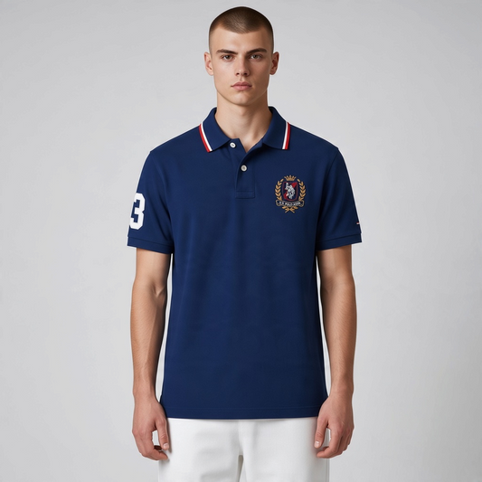 Hombre vistiendo polo azul marino de www.treshop.com.co con cuello a rayas, escudo bordado y número en la manga.