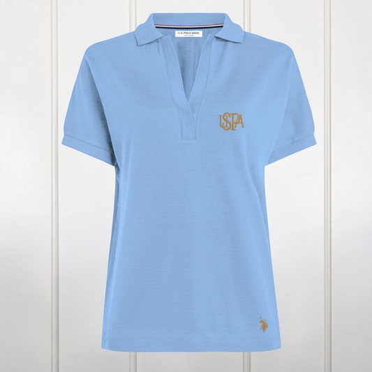 Polo azul claro para mujer de www.treshop.com.co con cuello en V, tejido de algodón y logo bordado en tono dorado.