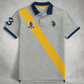 Polo www.treshop.com.co gris de algodón piqué con franja amarilla diagonal, logo bordado y número tres en la manga.
