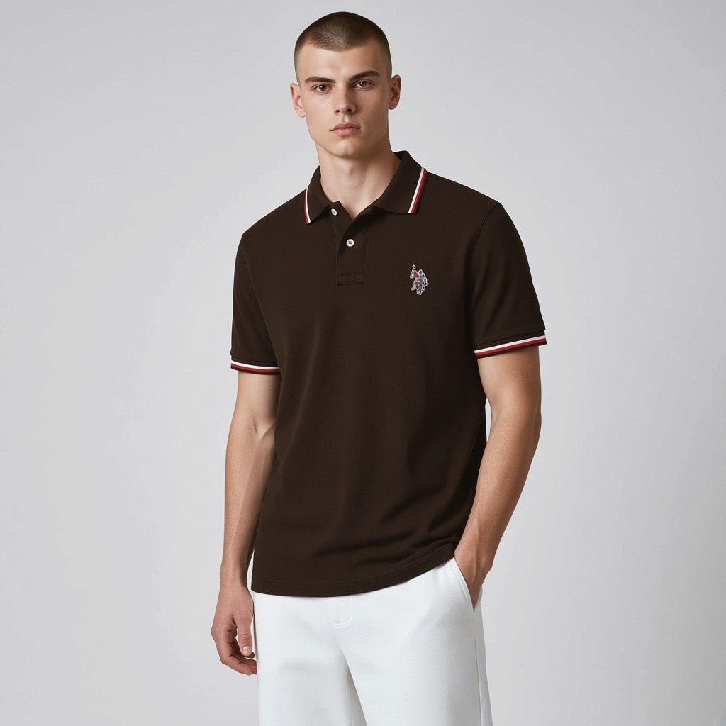 Modelo vistiendo polo marrón oscuro U.S. Polo Assn. con detalles en contraste en cuello y mangas y logo bordado